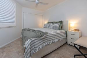 a white bedroom with a bed and a chair at Beach Street Oasis - Tuncurry in Tuncurry +17 photos