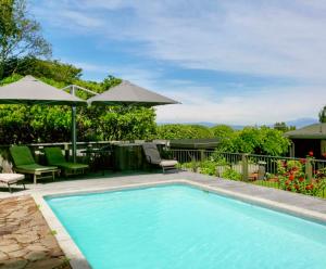a swimming pool with chairs and umbrellas at Iconic Taupō Views in Taupo