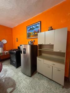 a kitchen with orange walls and a stainless steel refrigerator at Casa Nimacachi in Panajachel