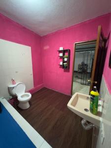 a pink bathroom with a toilet and a sink at Casa Nimacachi in Panajachel