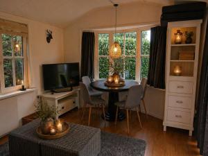 a living room with a table and a tv at Vechtdal Chalet de Berk in Rheezerveen +4 photos