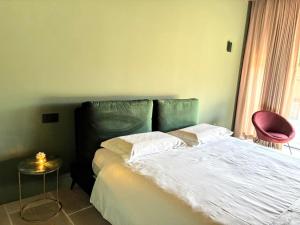 a bedroom with a bed and a pink chair at Elegant suite with porch and shared pool in Adro +21 photos