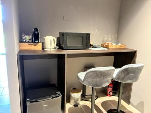 a desk with a microwave and two chairs at Elegant suite with shared pool in Adro