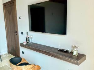 a television hanging on a wall with a wooden shelf at Elegant suite with shared pool in Adro