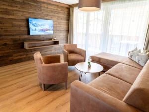 a living room with a couch and chairs and a tv at Spacious suite for 8 guests with a private sauna in Rauris