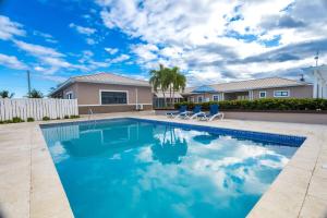 a swimming pool with two chairs and a house at Oceanpointe Luxury Retreat-3 Bedroom Home in Point