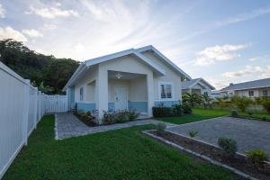 a white house with a fence and a yard at Oceanpointe Luxury Retreat-3 Bedroom Home in Point