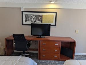 a desk with a monitor and a chair in a hotel room at Exceed Inn Indianapolis Airport South in Indianapolis