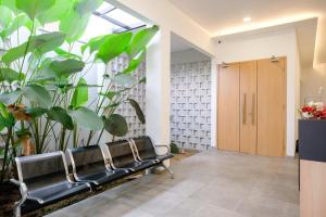 a row of benches in a hallway with plants at Urbanview Hotel Subali Purwokerto in Purwokerto