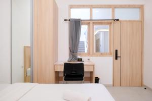a bedroom with a desk and a window at Urbanview Hotel Subali Purwokerto in Purwokerto