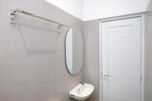 a white bathroom with a sink and a mirror at Urbanview Hotel Subali Purwokerto in Purwokerto +55 photos