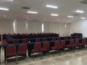 a conference room with a long table and red chairs at Hotel Mirante São Brás in São Brás do Suaçuí
