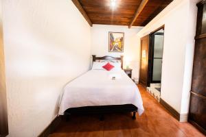 a bedroom with a white bed with a red pillow at Los Faroles Hotel & Spa in Antigua Guatemala