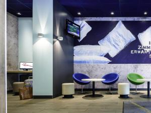 a lobby with two tables and a tv on a wall at Ibis budget Berlin Potsdamer Platz in Berlin