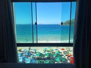 a view of a beach with umbrellas from a window at Loft Prainha in Arraial do Cabo