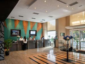 a lobby of a hotel with people standing at a counter at Novotel Santiago Vitacura in Santiago