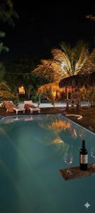 a swimming pool at a resort with a wine glass at Chalé Com Piscina Privativa in Fortim