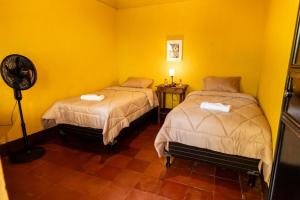 two beds in a room with yellow walls at Hotel Itzel in Cobán +9 photos