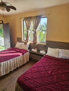 a bedroom with two beds and a window at Habitaciones Casa Cuscatlan in Tamanique