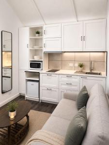 a white kitchen with a couch and a table at Cosy Studio- Blue Mountains in Wentworth Falls