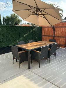a wooden table with chairs and an umbrella at Chic East LA Retreat 2 bedroom-sleeps 6-Near DTLA-Car Rental Service on Property in East Los Angeles