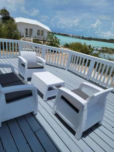 a deck with white chairs and a table and a table at Swan cottages #6 Waterfront in Providenciales
