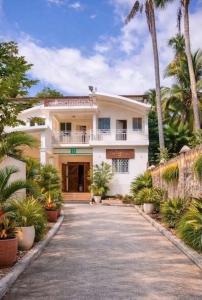 ein großes weißes Haus mit Palmen und einer Auffahrt in der Unterkunft Mozard Hotel in Cayes Jacmel