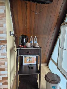 a small table with a tea kettle and water bottles on it at Orchid Chalet in Ringlet