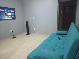 a blue couch in a living room with a tv at pajuçara R2 in Maceió
