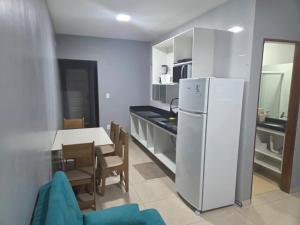 a kitchen with a white refrigerator and a table with chairs at pajuçara R2 in Maceió
