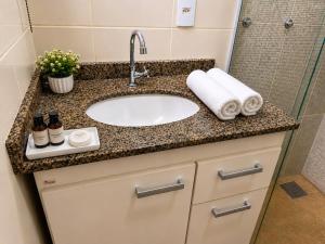 a bathroom counter with a sink and a shower at Flat 2 quartos em residencial | Ar e garagem in Ourinhos