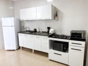 a white kitchen with a stove and a refrigerator at Flat 2 quartos em residencial | Ar e garagem in Ourinhos