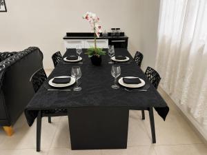 a black table with plates and wine glasses on it at Flat 2 quartos em residencial | Ar e garagem in Ourinhos +13 photos
