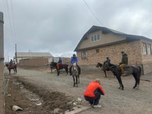 a group of people riding horses on a dirt road at CBT1 Hotel in Sary-Mogul