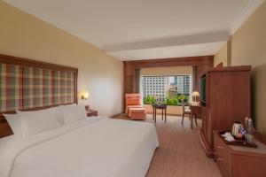 a bedroom with a large white bed and a window at Hotel Cambodiana in Phnom Penh