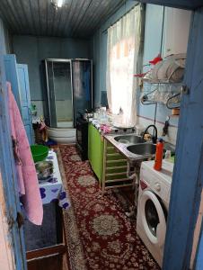 a dirty kitchen with a sink and a washing machine at Эламан in Otradnoye