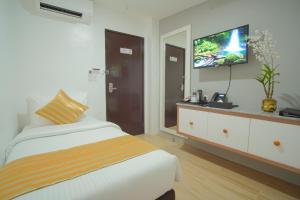 a bedroom with a bed and a flat screen tv at Ragazzi Resort Hotel in Naga