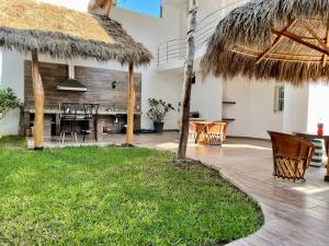 a patio with a table and chairs and a thatch roof at Bungalows Mufrance in San Patricio Melaque