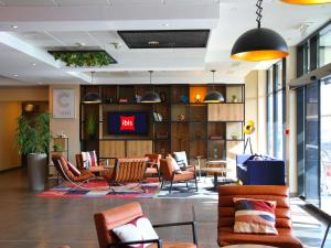 a lobby with chairs and a tv in a building at ibis Beauvais Aéroport in Beauvais