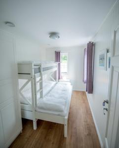 Viken Holiday Home في Viksdalen: سرير بطابقين أبيض في غرفة مع أرضيات خشبية