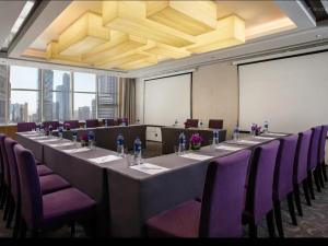 a conference room with a long table and purple chairs at Mercure Dalian City Center in Dalian