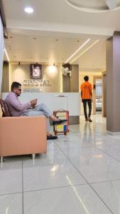 two men sitting on a couch in a lobby at Hotel Crystal in Ahmedabad