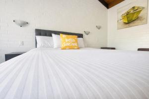 a white bed with a yellow pillow on it at Jetty Motel The Entrance in The Entrance +55 photos