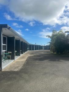 eine Reihe grüner Gebäude mit Tischen und Stühlen in der Unterkunft The Awanui Hotel in Awanui