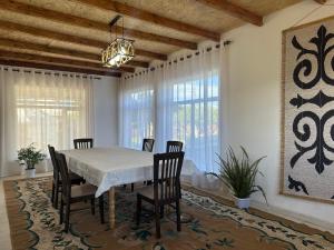 a dining room with a white table and chairs at Gulazyk guest house in Bokonbayevo