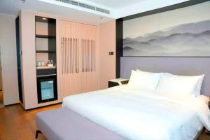 a bedroom with a white bed and a painting on the wall at Mercure Dalian City Center in Dalian +25 photos