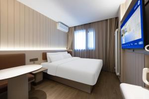 a hotel room with a bed and a tv at Hanting Hotel Beijing Xizhimen in Beijing