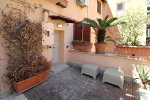 ローマにあるLHP Suite Roma Trastevereの白いベンチ2台と鉢植えの植物がある中庭