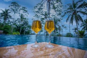 two glasses of wine sitting on a table next to a pool at Cinnamon View Galle in Galle