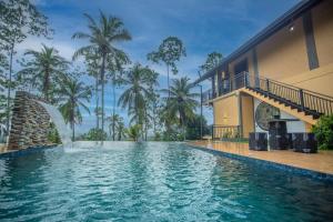 a swimming pool in front of a house with a fountain at Cinnamon View Galle in Galle